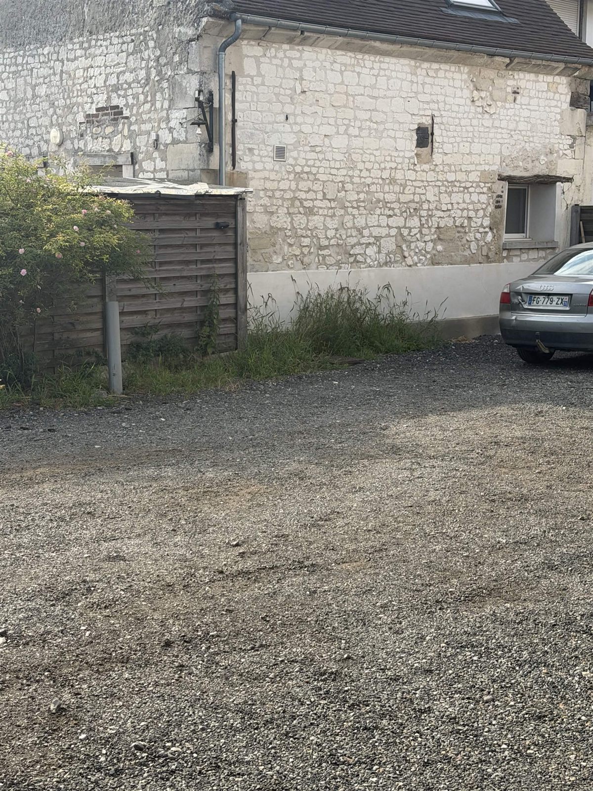 Grande cour gravillonnée avec végétation avant intervention